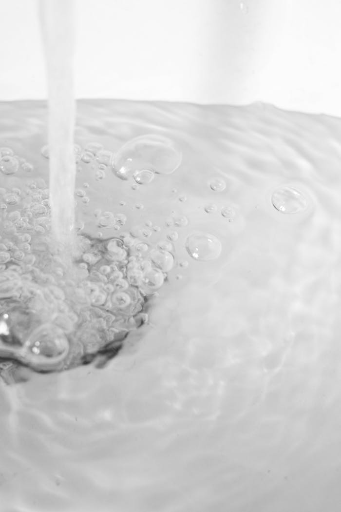 Close-up of water with bubbles flowing into a kitchen sink, creating a refreshing and clean atmosphere.