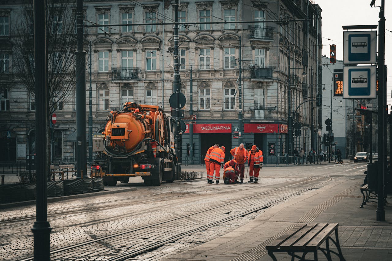 City workers repairing tram tracks on Piotrkowska Street in Łódź, Poland, amidst classic architecture.